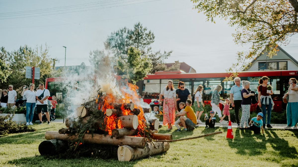 A lively community gathering enjoying a bonfire event outdoors on a sunny day.